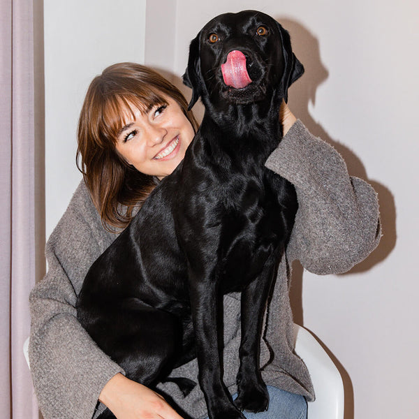 Frau mit einem schwarzen Labrador auf dem Schoß